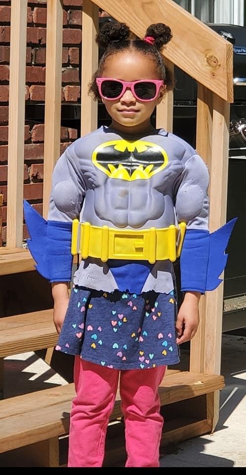 Girl with sunglasses and batman costume standing